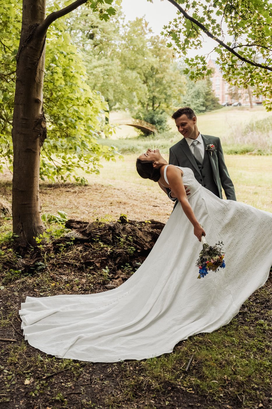 Trouwfoto — koppel in dip-pose onder boom, jurk in beweging