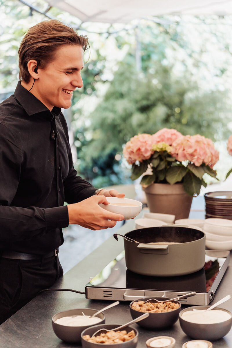 Vriendelijke medewerker van Park Ven serveert een ontbijtbuffet met verse pap en toppings