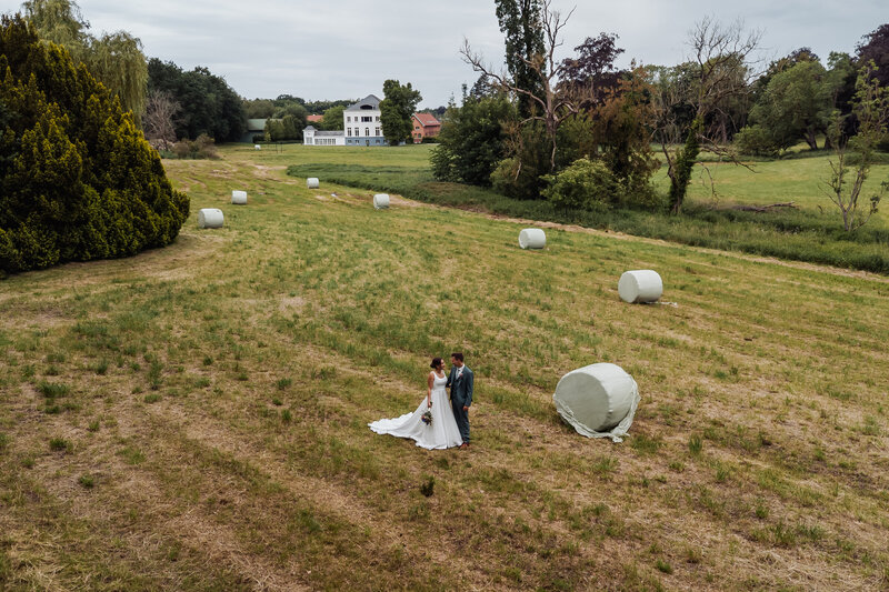 Luchtfoto van bruidspaar in een zonnig veld nabij De Waerboom